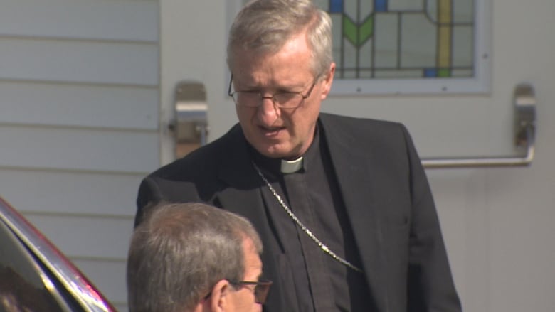 A man in a black priest suit with white collar.