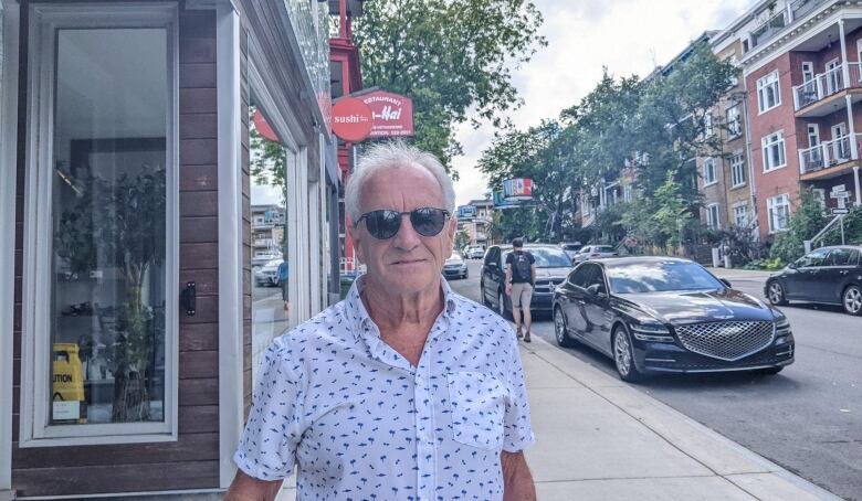 A man standing on the sidewalk on a street in Quebec City.