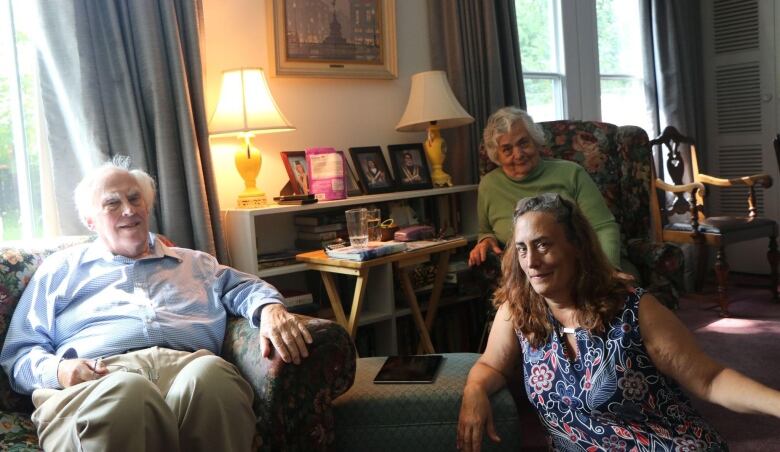 A woman and her parents are pictured sitting in a living room.