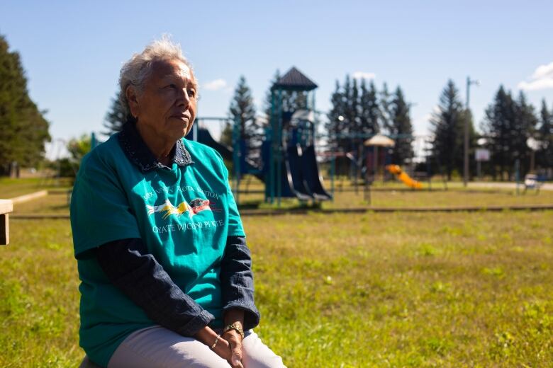 An elder sits on a bench looking out into the distance.