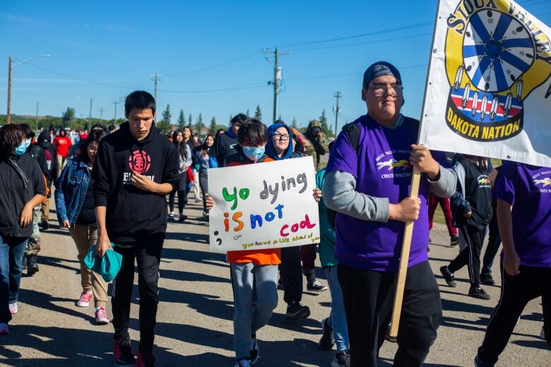 Students walk holding signs for World Suicide Prevention day.