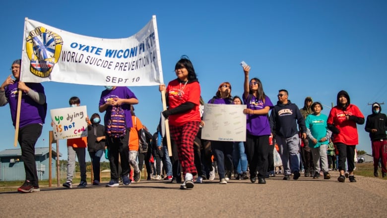 Young students walk together hold signs promoting World Suicide Prevent Day.