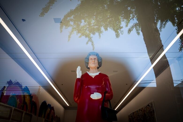 A model of Queen Elizabeth the second. The model's hand is held up in what appears to be a wave.