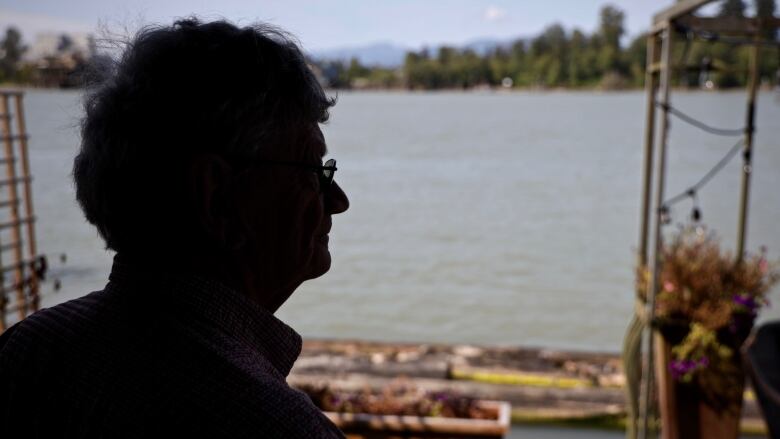 MacLeod is seen in silhouette in the background of a river.