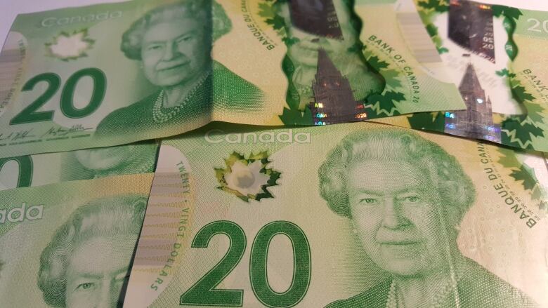 Several green $20 Canadian bank notes with the face of the Queen.