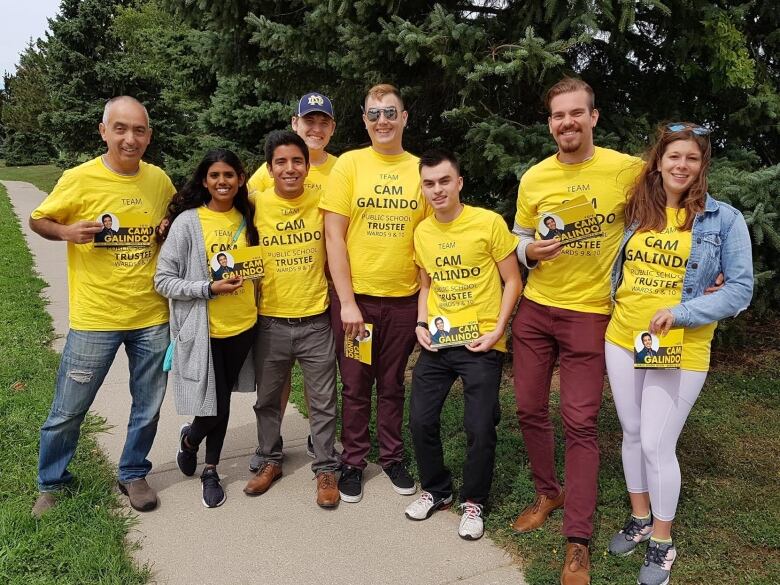 A group of eight people stand together, all wearing shirts with Cam Galindo's name on them. 