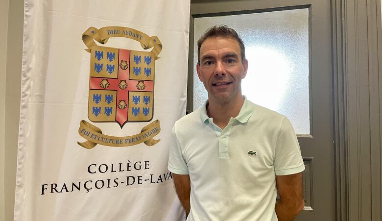 A man standing in front of a school flag.