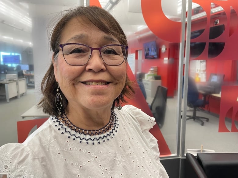 Smiling woman in glasses in front of CBC backdrop. 