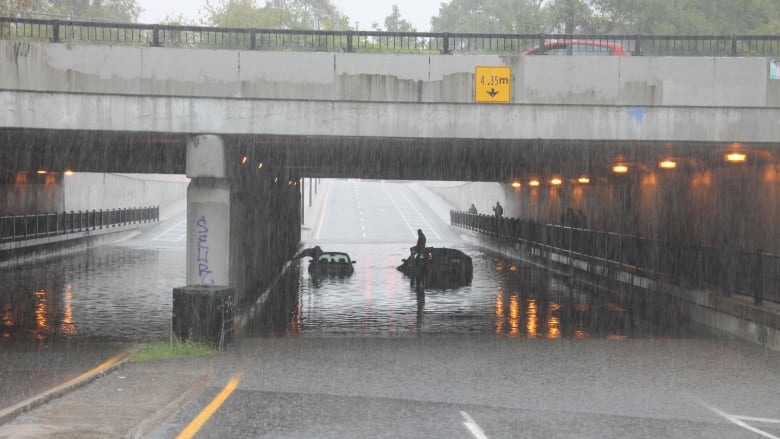 A bridge, an underpass, two cars stuck in about 30 cm of water.