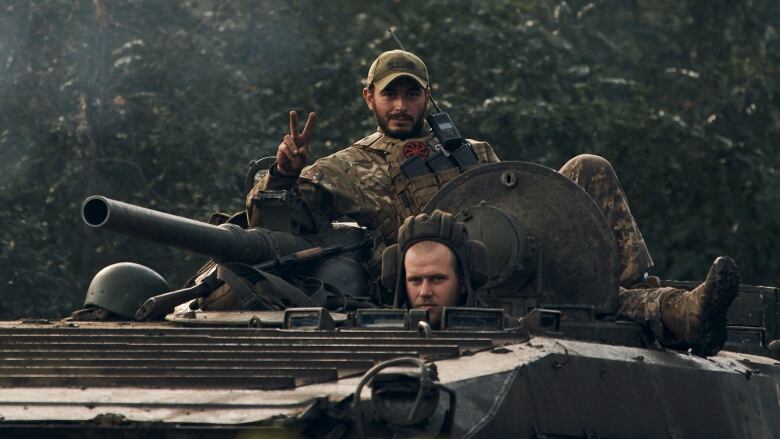 A soldier sits on top of a tank