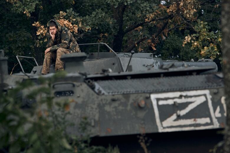 A Ukrainian soldier sits on top of a tank