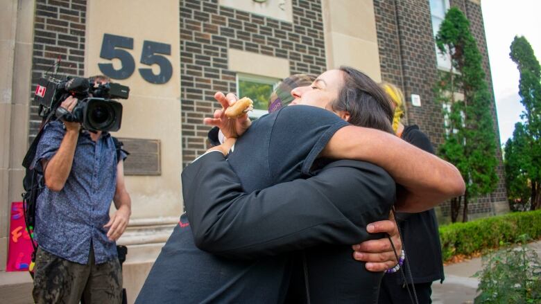 A man hugs a person in a suit.