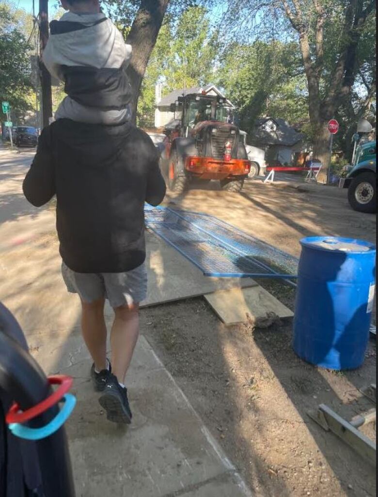 A man walks through a construction area holding a small child.