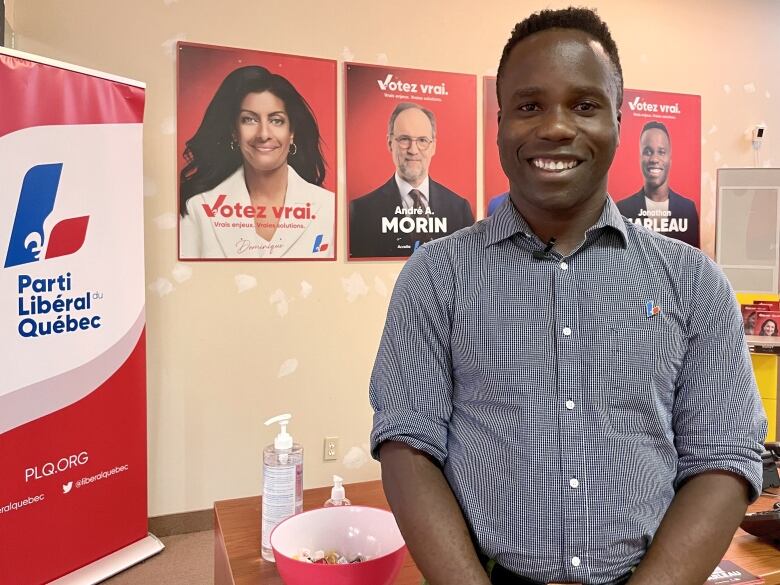 A man stands in front of three signs. 