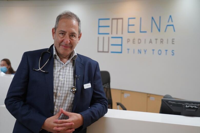 A man stands in front a sign for his medical clinic 