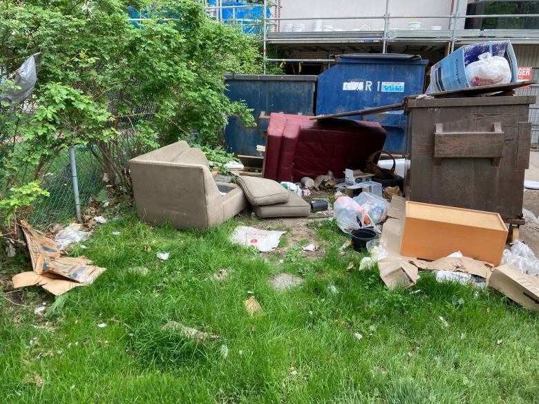 A pile of garbage, including a discarded couch, sits outside the building.