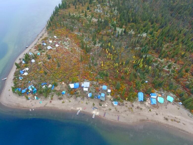 A birds-eye view of a camp set near the shores of a body of water.