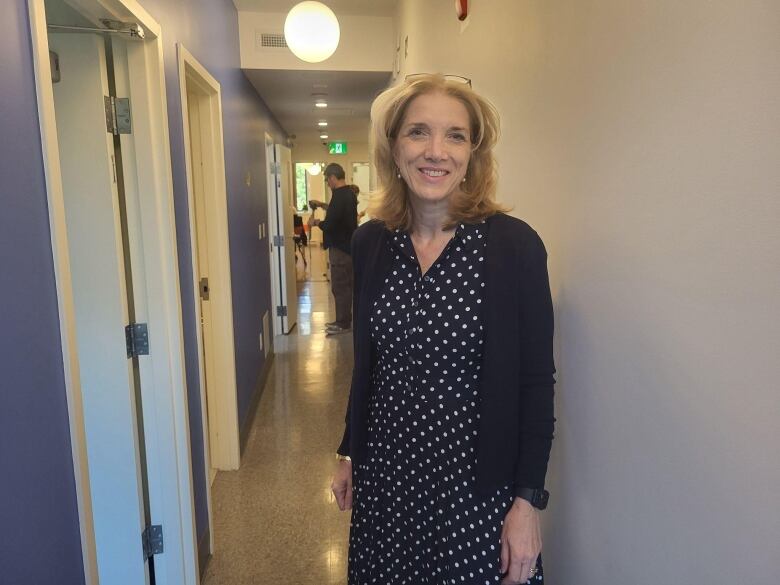 Marina Boulos-Winton wearing a black and white polka-dot dress standing in the shelter's hallway.