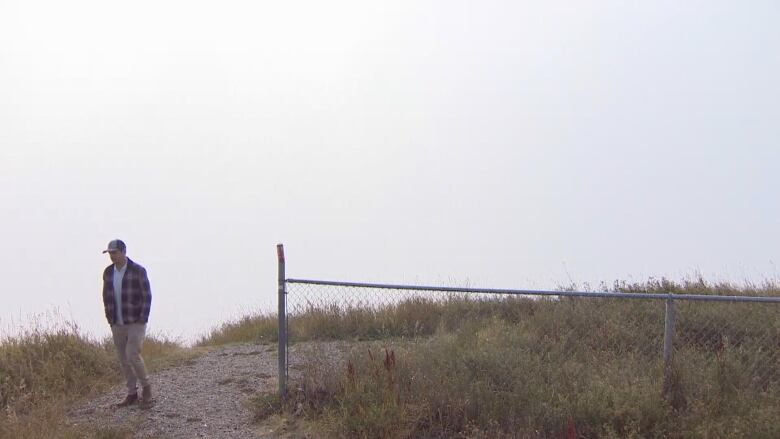 A blanket of smoke obscures the view from a hill, with a hiker on it.