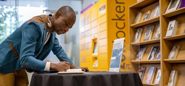 Benjamin Ansah signs the Queen's condolence book at Canning Town Library.