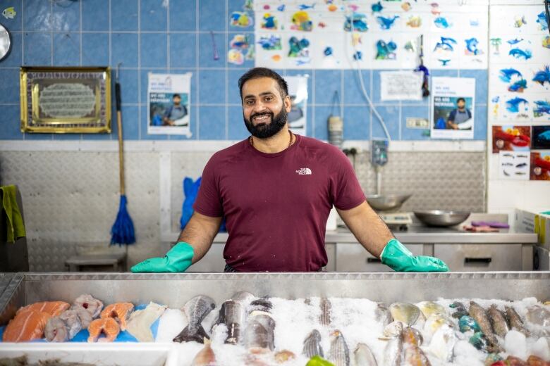 A man stands behind a fishmonger's stall in a market.