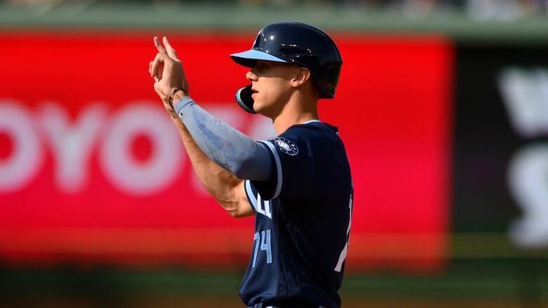 A baseball player holds up his hands in celebration.