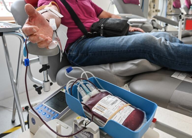 person sits in chair as plasma is drawn out through tube into bag