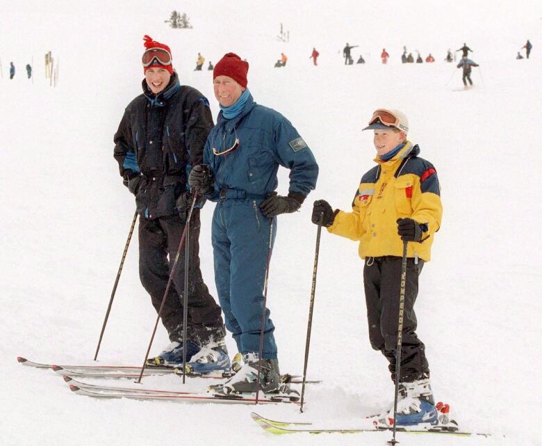 Three people stand on skis on a snow-covered mountain.