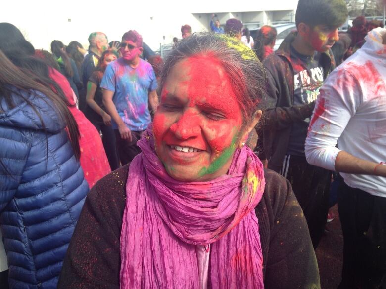 A woman's face is covered in red and green powder.