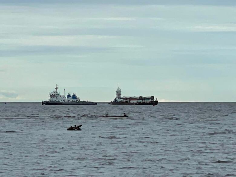 Two large boats seen distantly on an open body of water.