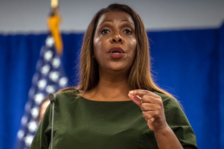 A woman shown in closeup gestures and speaks while standing.