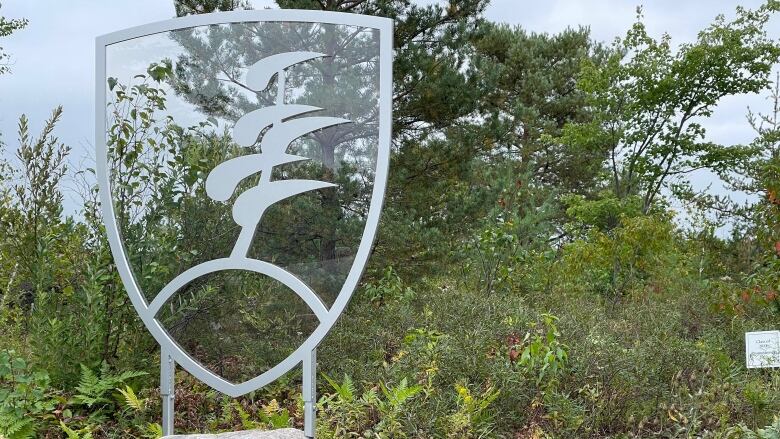 A glass sculpture of a shield with a tree on a rock.