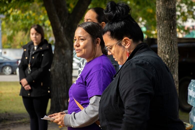 A woman hold a paper speaking to a crowd.