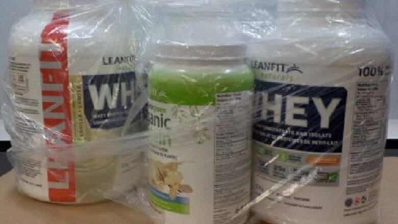 Three bottles marked 'whey' and 'protein' are wrapped with cling film.