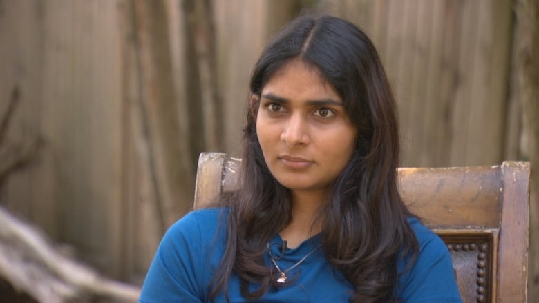 A South Asian woman stares intently while sitting down.