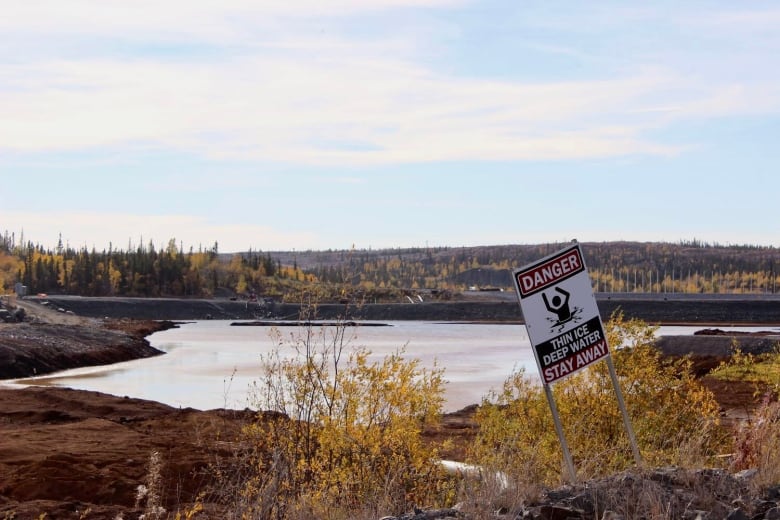 A pond in the fall with a sign that says 