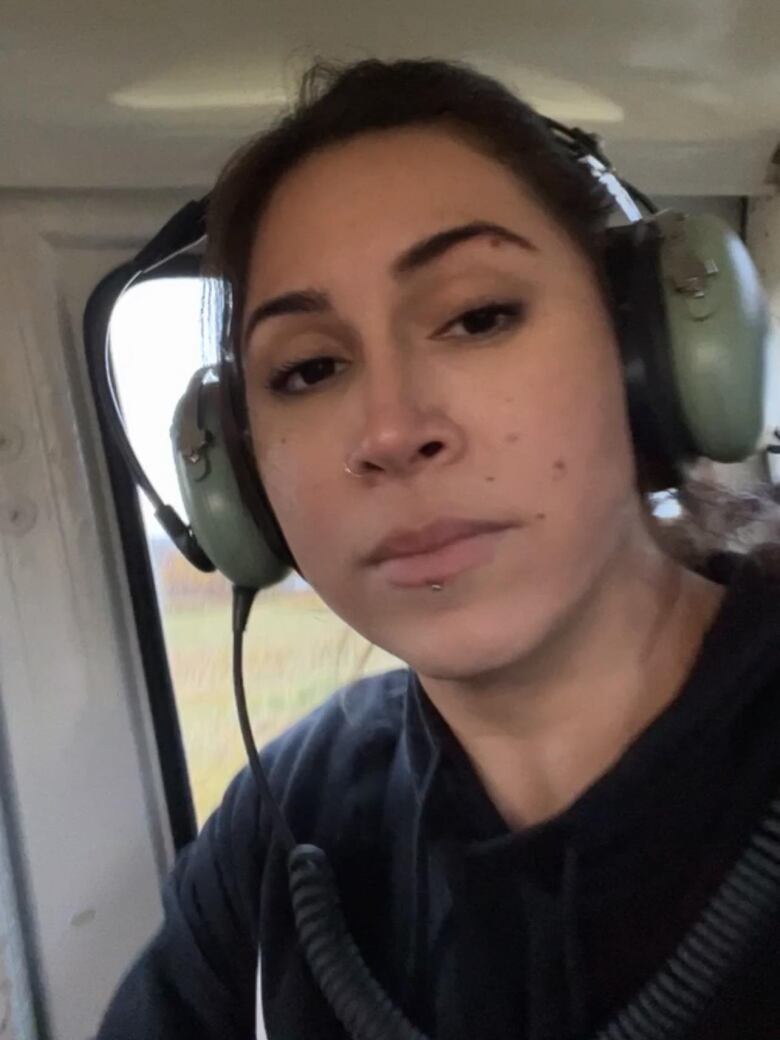 Woman sitting in a helicopter with an unhappy look on her face.