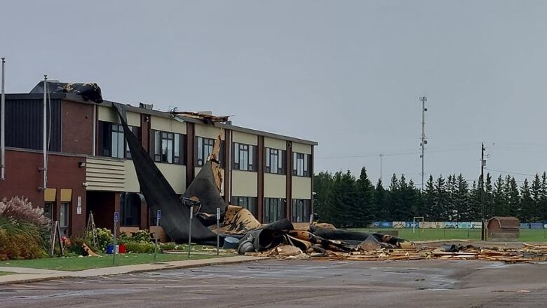 School building with large chunks of its roof torn off and hanging down. 