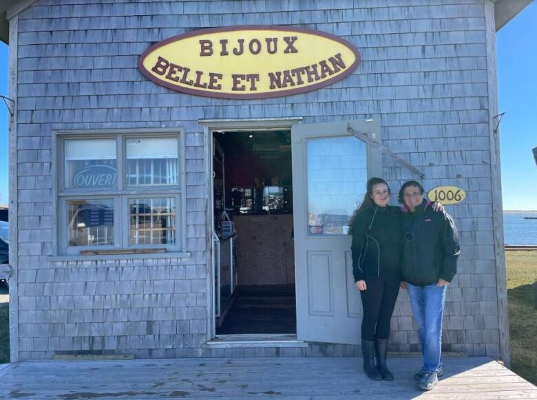 A mother and daughter standing outside a seaside shop. 