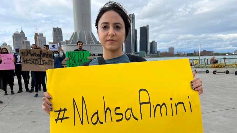 Naz Reihani holding sign that says hashtag Mahsa Amini