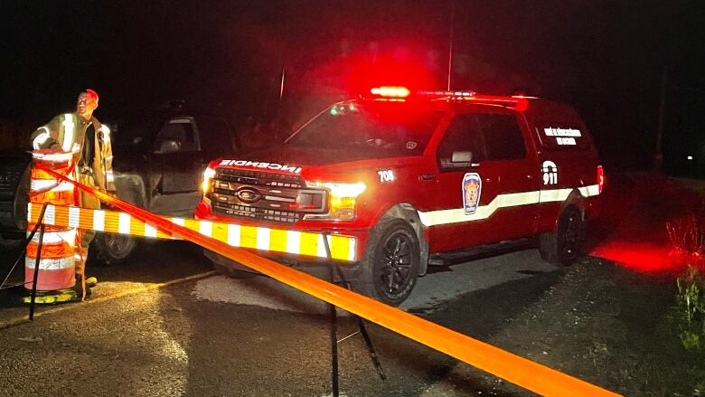 A first responder next to a vehicle parked next to a fire department SUV.