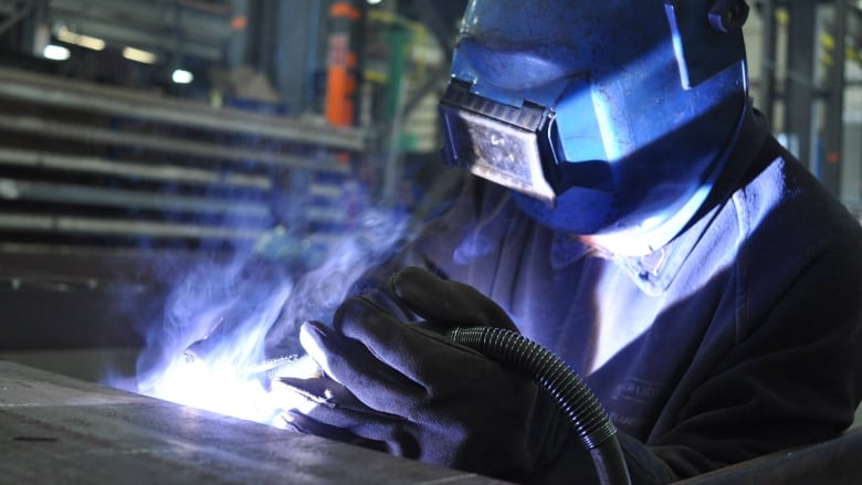 A man with a mask works with a welding torch. 