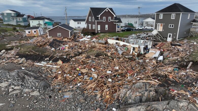 An aerial drone photo shows debris from destroyed homes scattered over the rocky cliffs of Port aux Basques, NL. 