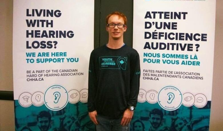 A man stands in front of banners.