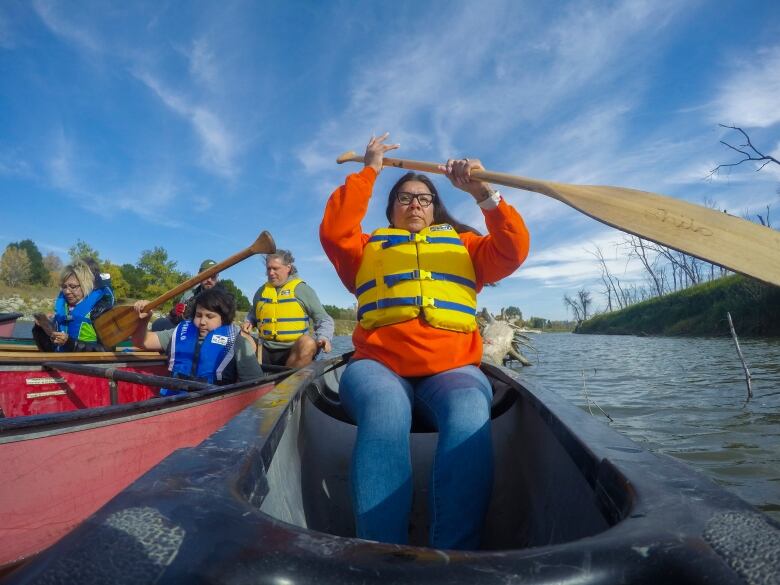 A woman paddles a canoe.