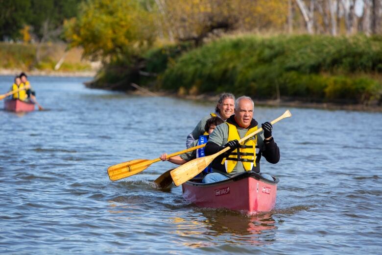 A canoe with people moves down the water.