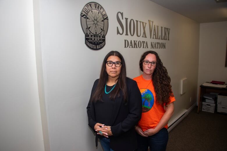 Two women stand in front of a Sioux Valley Dakota Nation sign.