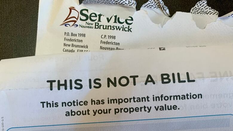 A ripped envelope with Service New Brunswick's address on it with a piece of a paper on top of it that says 