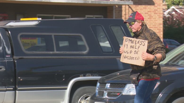 A panhandler works the intersection of Ouellette Avenue and Tecumseh Road.