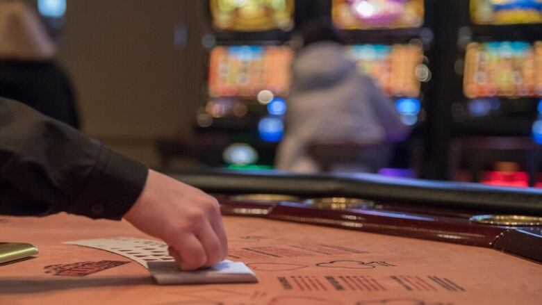 A closeup of a croupier's hand as she lays out playing cards on a gaming table.